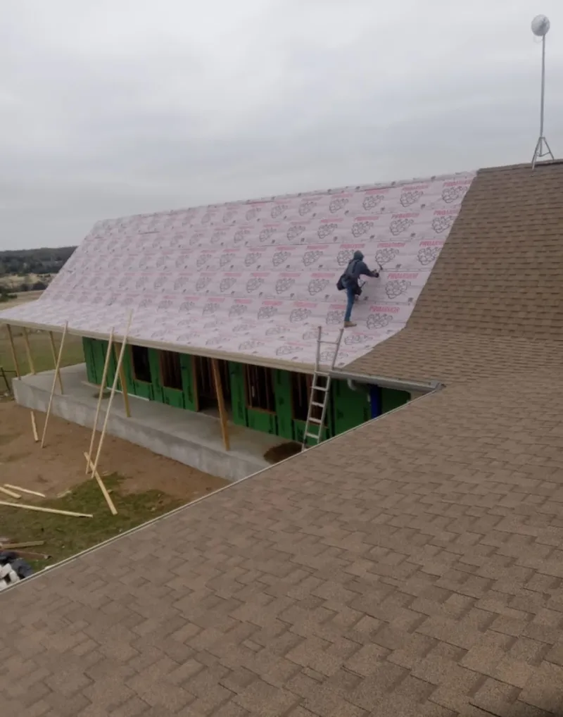 Worker preparing underlayment for a metal roof installation in Decatur